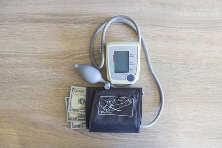 Money dollars lie with a tonometer on the table in the hospital. Expensive medicine and a tonometer apparatus lies on the table.の写真素材