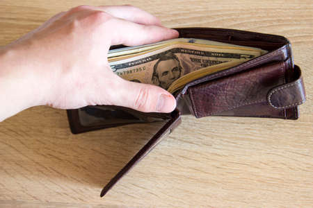 Man showing wallet to camera with money. Money dollars lie in the wallet that the man holds.の写真素材
