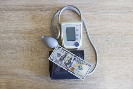 The tonometer device lies near the dollars on the table. Money lies next to a blood pressure...