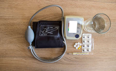 A glass of water and pills near the tonometer.の写真素材