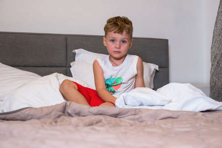 Boy sitting in the bedroom in pajamasの写真素材