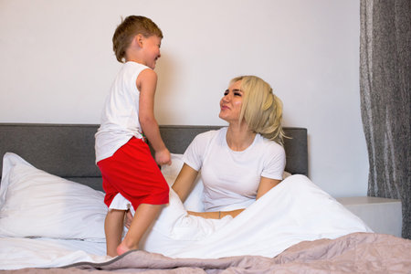 Mom with little son playing in the bedroom.の写真素材