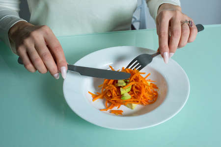 Girl sits and eats a delicious and healthy salad.の写真素材