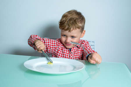 Boy cuts a piece of vegetable on a plate.の写真素材