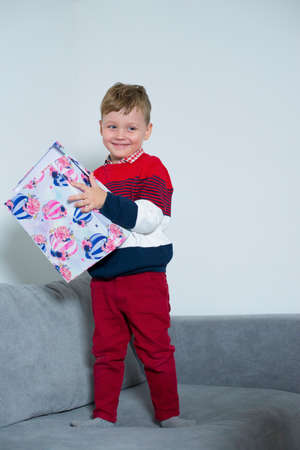 Boy smiles while holding a big gift in his hands.の写真素材