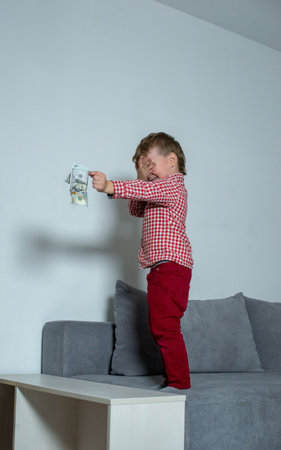 Boy with dollars in his hands stands on the bed.の写真素材