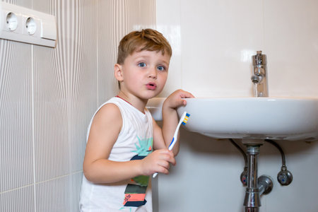 Little boy stands near the washbasin in bathroom.の写真素材