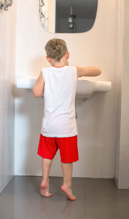 Child stands near the sink and washes his hands.の写真素材