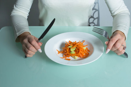 Girl eats healthy salad in the kitchen.の写真素材