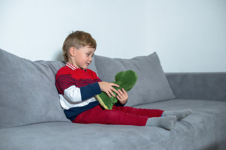 Little boy sitting on bed and playing with a toy.の写真素材