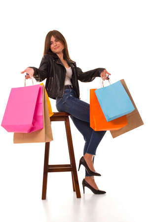 Surprised girl with packages in hands sit on chairの写真素材
