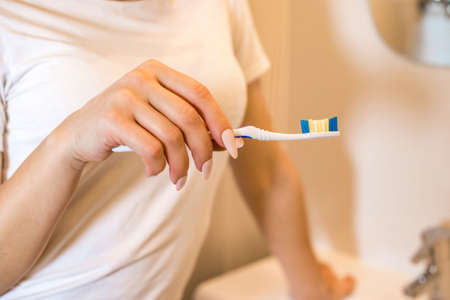 Girl with a toothbrush stands in the bathroom.の写真素材
