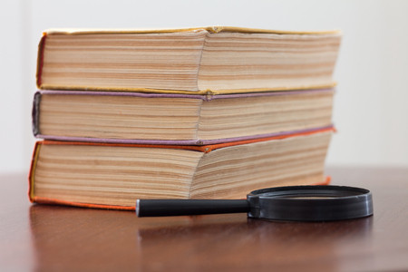 A pile of books and a magnifying glassの写真素材