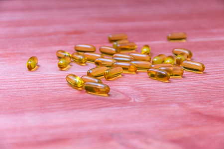 capsules of fish oil on a wooden tableの写真素材
