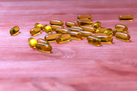 capsules of fish oil on a wooden tableの写真素材