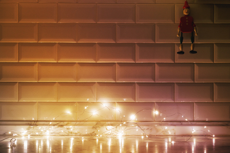 kitchen tiled wall, marble countertop, wooden doll and light from the garlandの写真素材