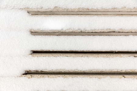 the back of a white wooden bench covered with snowの写真素材