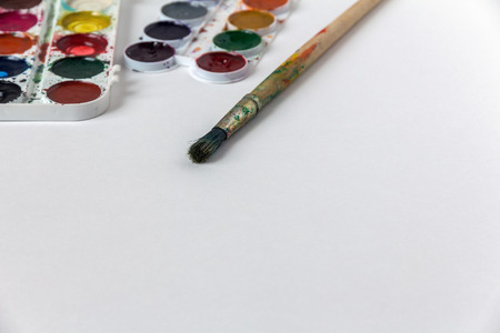 children's paints and a brush on white paperの写真素材
