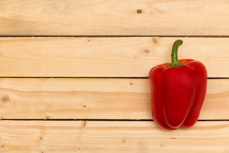 one big red pepper on a wooden tableの写真素材