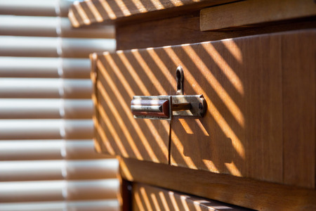old wooden chest of drawers in the sunlight through the blindsの写真素材