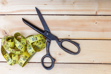 Old tailor's scissors and a centimeter on a wooden table