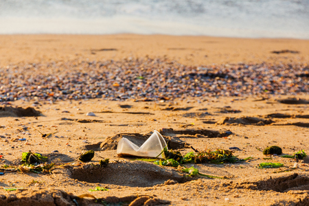 Wrinkled plastic cup in the sand on the beachの写真素材