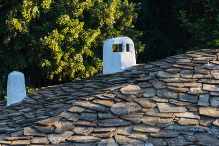 tiled roof of a house with a white pipeの写真素材