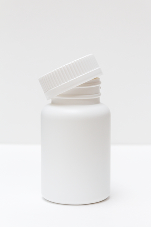white plastic bottle with cap for pills on a light backgroundの写真素材