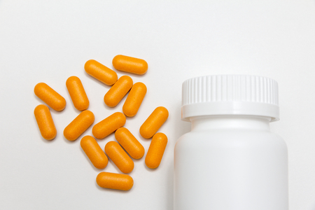 yellow pills and white plastic can on the tableの写真素材