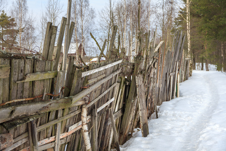 ragged old wooden fence with barbed wire.  path in the snow along the rural fence. non urban winter landscapeの写真素材