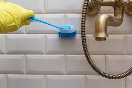 cleaning the tile in the shower room with a brushの写真素材