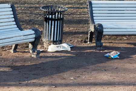 trash scattered around the urn. garbage near the benches in the city park. environmental pollutionの写真素材