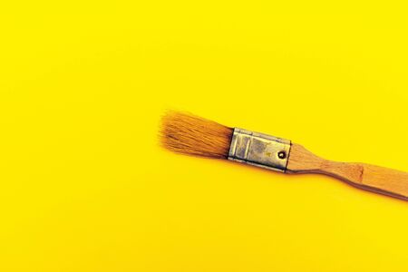 Old art brush on a yellow canvas. Concept of creativity, hobby and workshop. Painting works. Free space for image and text.の写真素材