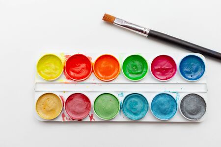 Children's watercolor paints and brush in a white box on a light background. The concept of creativity and learning of the childの写真素材
