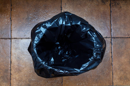 Empty new black plastic trash bag on a bucket in a room with ceramic tiles. The concept of cleaning...
