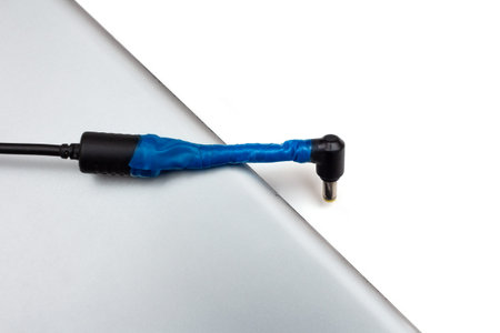 broken and repaired by an insulating tape power adapter on a laptop cover not plugged into a socket