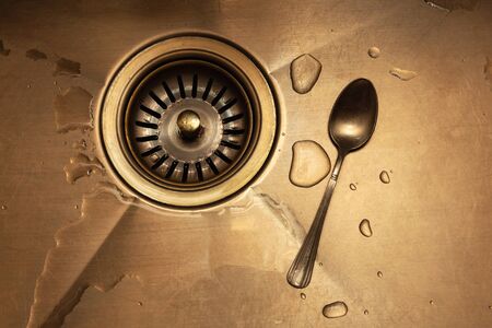 teaspoon in a kitchen sink close-up. concept of family quarrel or lonelinessの写真素材