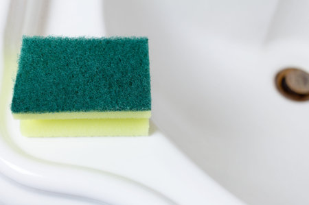 cleaning sponge on the edge of a snow-white shining marble sink in the bathroomの写真素材