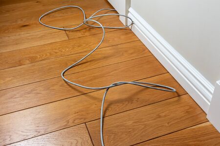 connecting patch cord on the parquet floor of the room along the wall. uncomfortable wiring internet in the apartmentの写真素材