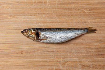 one smoked herring on a wooden cutting board. minimalistic still life. fishing concept