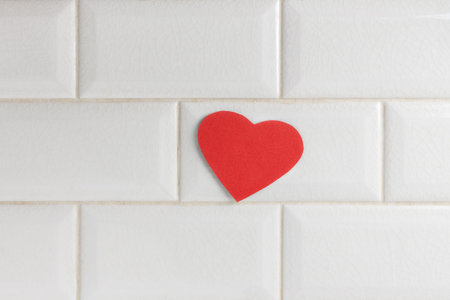 red heart made of paper on a white tiled wall. a pleasant surprise for your loved one. Healthy heart care conceptの写真素材