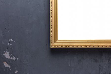 A fragment of a vintage gilded wooden picture frame with a white background inside on a dark background of an old stucco wall. can use put picture or textの写真素材