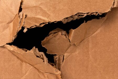 damaged cardboard box with a black hole. damage in the delivery of parcels and shipmentsの写真素材