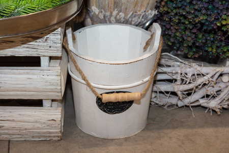 Empty wooden bucket with a rope handle on the floor of a flower shop on the background of decorative...