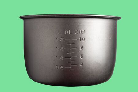 Old saucepan for a slow cooker with a measuring scale on a green background. Pan for multicookerの写真素材