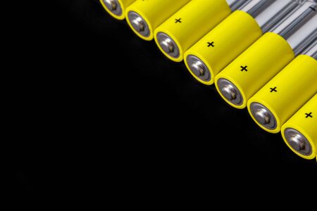 A row of gray-yellow AA alkaline batteries on a black background. Use and disposal of NiMH batteries.  Copy space.の写真素材