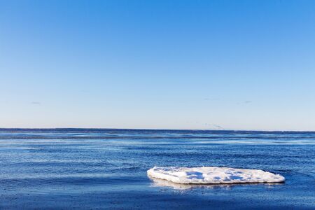 Floating ice floe in cold blue water against a clear spring sky. Global warming conceptの写真素材