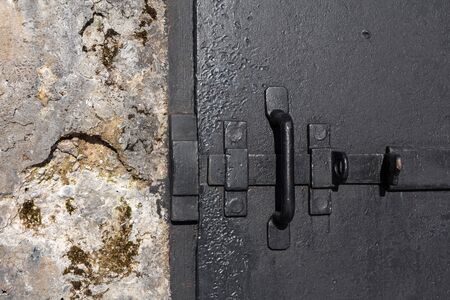 deadbolt on a heavy iron door in an old concrete wall of an army bunkerの写真素材