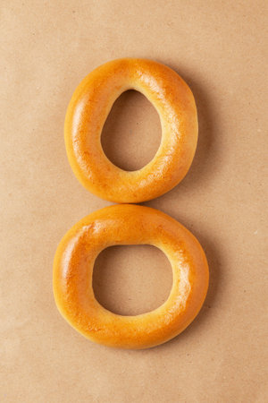 Two fresh round bagels are folded in the shape of the number eight on packing paper. Industry of...