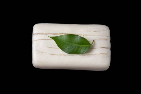 Green leaf on a piece of dry soap with cracks. Black background with place for text. The concept of hand washing and the fight against germs of the virusの写真素材